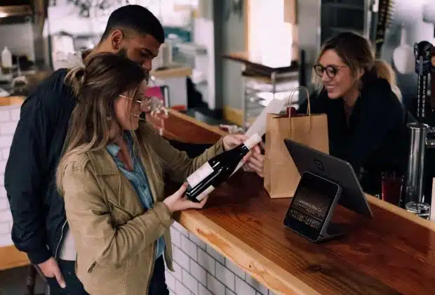 woman holding wine bottle beside man in front of woman smiling