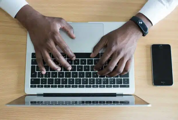 person's hand on MacBook near iPhone flat lay photography